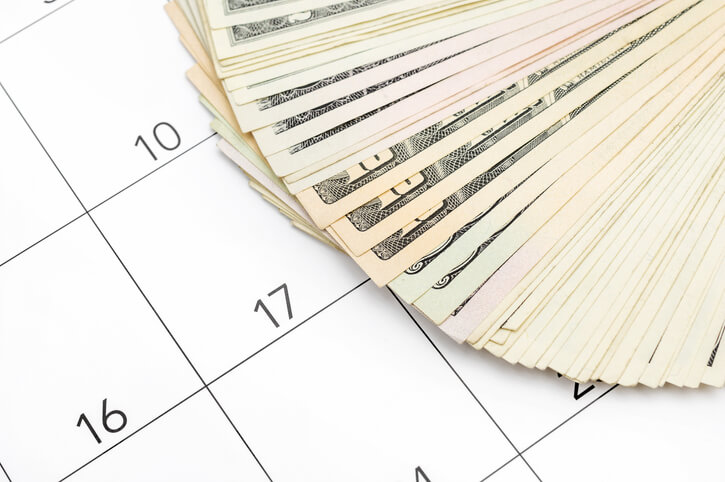 dollar bills spread out on calendar