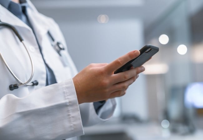 Clinician exploring the locum tenens credentialing process on their smartphone Clinician exploring the locum tenens credentialing process on their smartphone