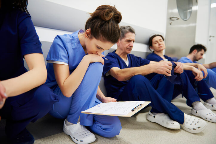 healthcare professionals sitting in hallway, looking glum or tired healthcare professionals sitting in hallway, looking glum or tired