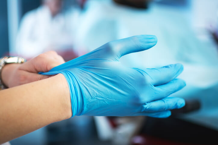 Close up of nurse putting on blue surgical gloves