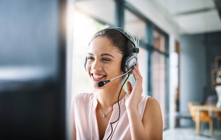 smiling woman on phone headset looking at computer