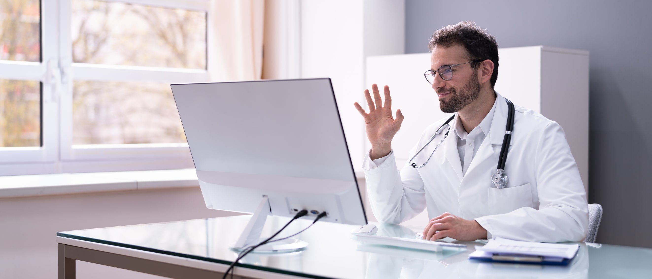 Doctor in white coat having video conference on computer