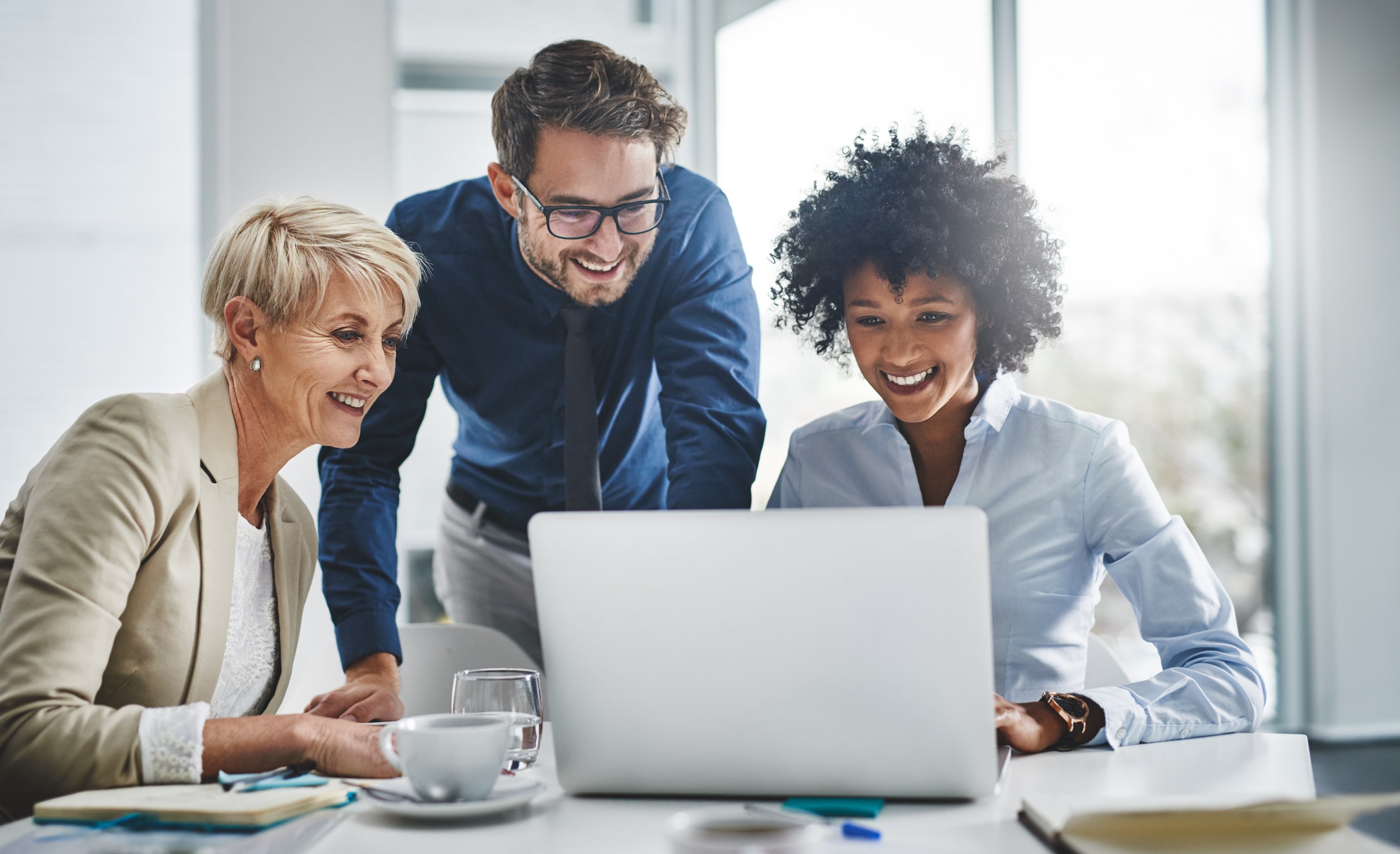 Healthcare executives gathered around a laptop doing work Healthcare executives gathered around a laptop doing work