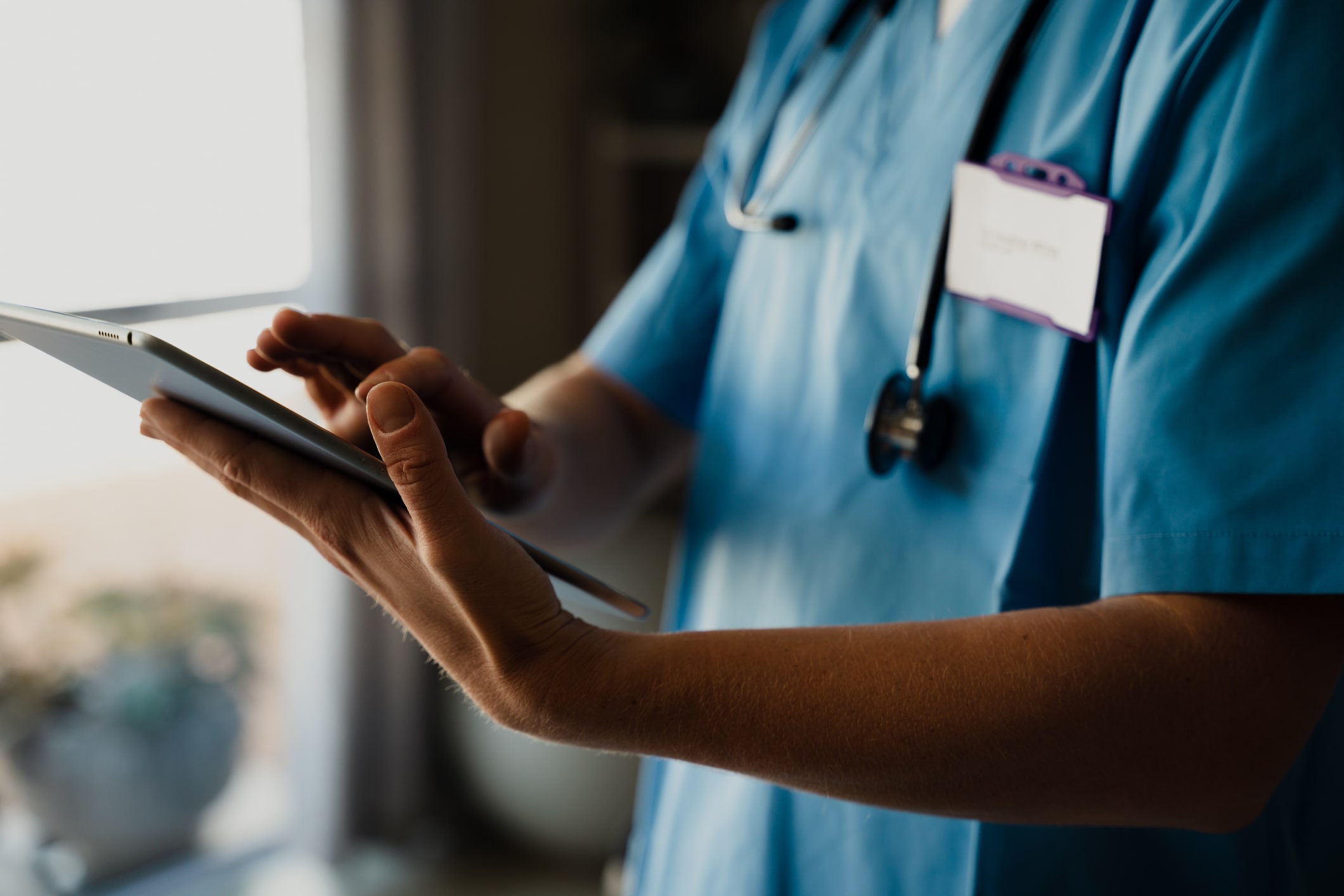 male nurse in blue scrubs works on ipad male nurse in blue scrubs works on ipad