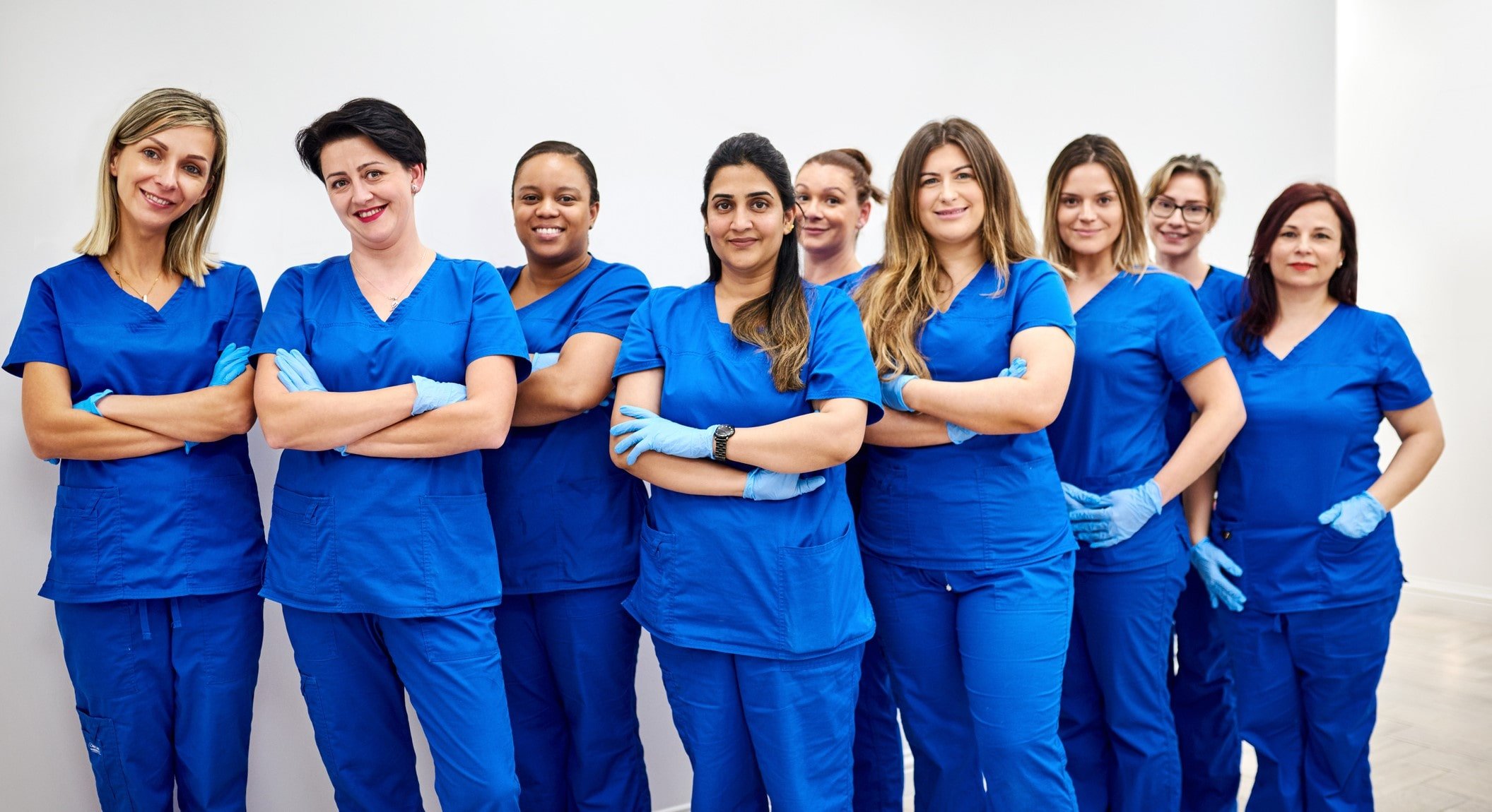 twelve or more female nurses in blue scrubs standing side by side with arms folding twelve or more female nurses in blue scrubs standing side by side with arms folding