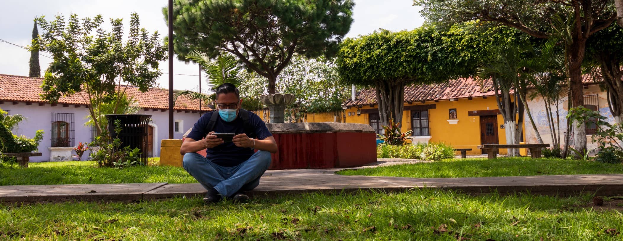 man sits on curb on ohone in guatemala 