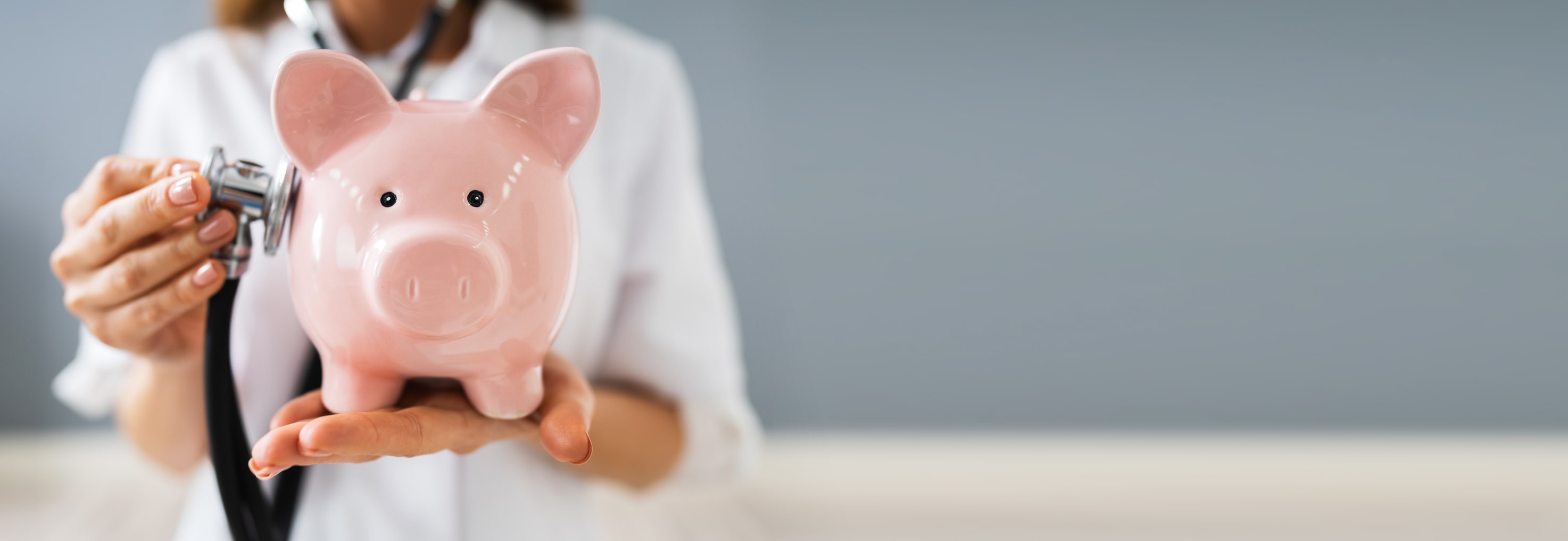 doctor in white coat holding pink piggy bank doctor in white coat holding pink piggy bank