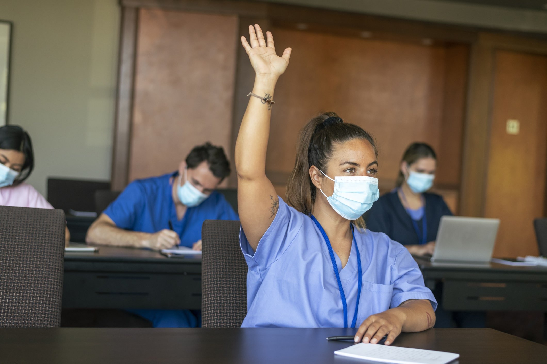 Nurse raising hand in classroom setting Nurse raising hand in classroom setting