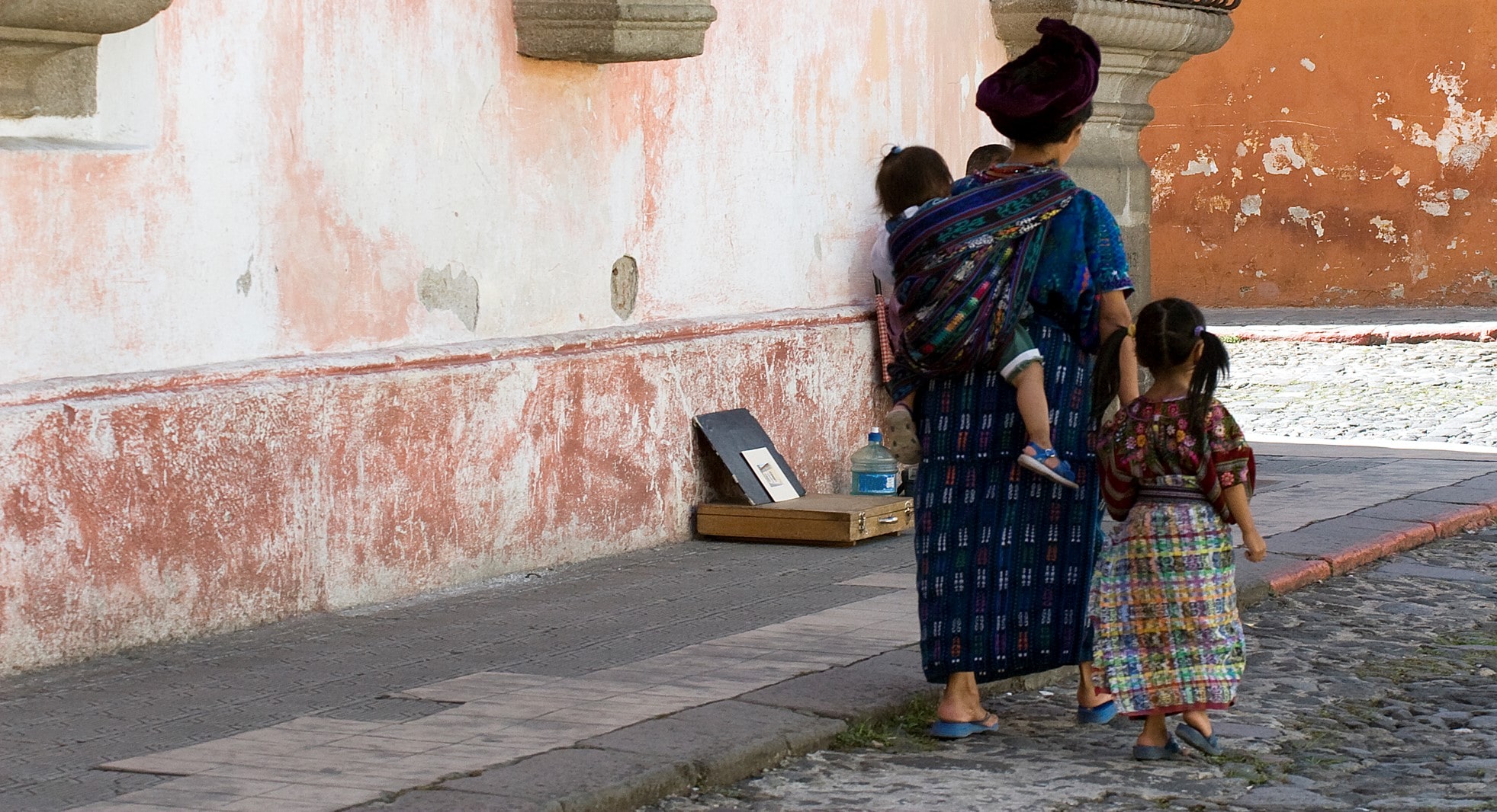 woman walks down street in guatemala with young children woman walks down street in guatemala with young children