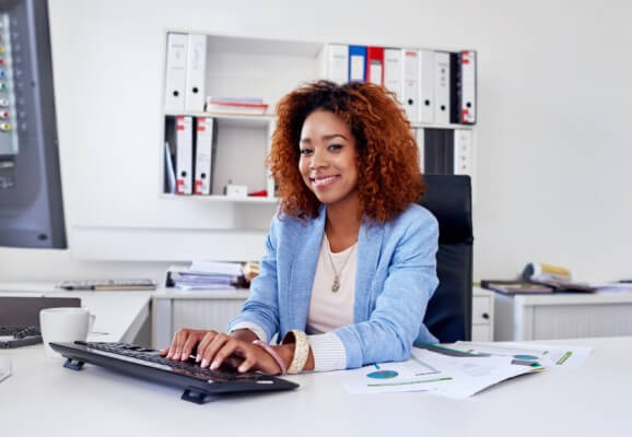 Smiling female professional working at desk with hands on computer keyboard