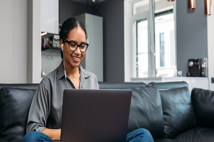 woman wearing glasses siting on coach with her computer