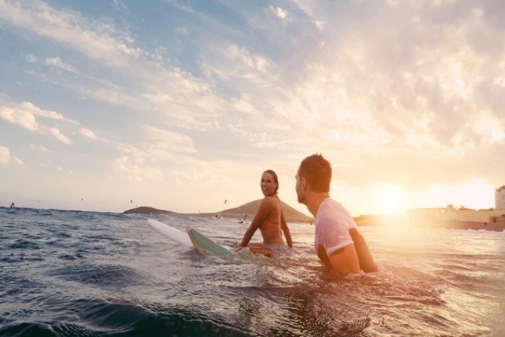 Couple sitting on a surfboard in ocean