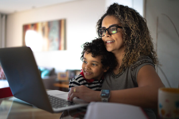 woman working on laptop at home with her son on her lap woman working on laptop at home with her son on her lap