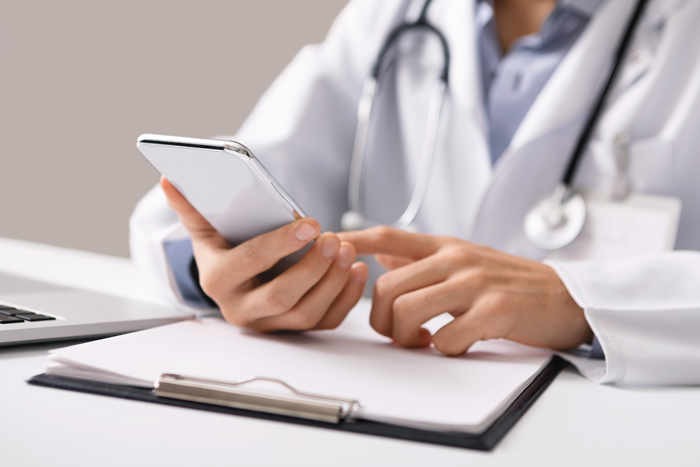 a medical professional sitting down at a desk and using their phone a medical professional sitting down at a desk and using their phone