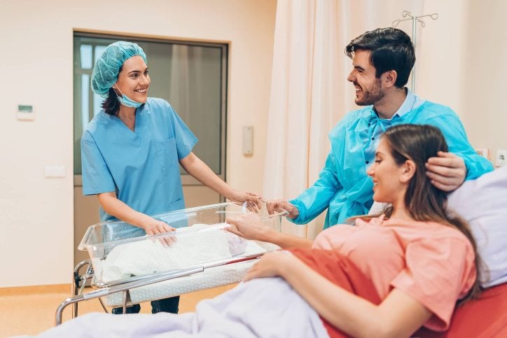 nurse in delivery room with woman and man