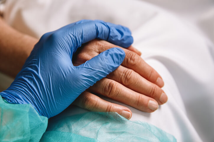 Healthcare worker holding patient's hand in a hospital setting
