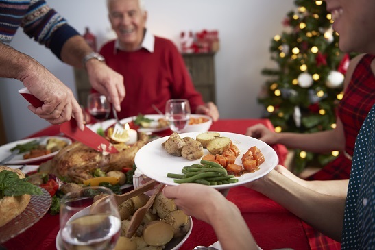 a table full of food with someone cutting a turkey and someone else holding a plate full of food