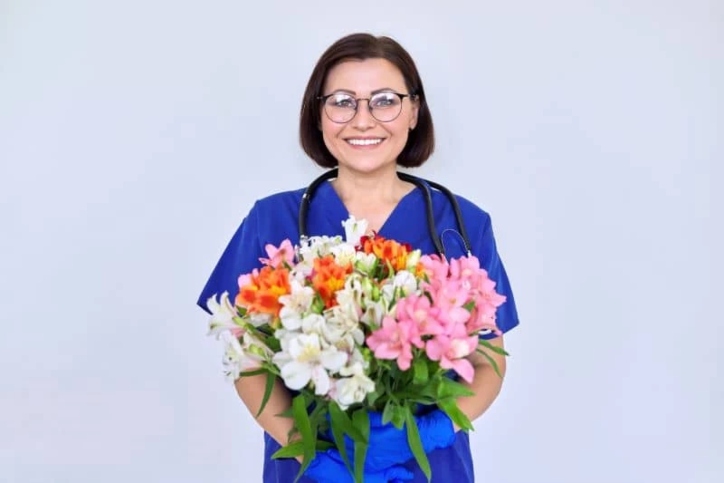 A healthcare professional holding a bouquet of flowers