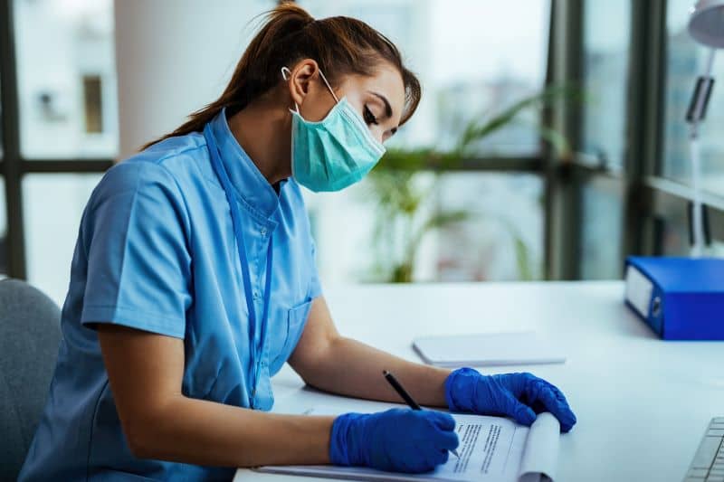 Nurse sitting at a desk writing Nurse sitting at a desk writing