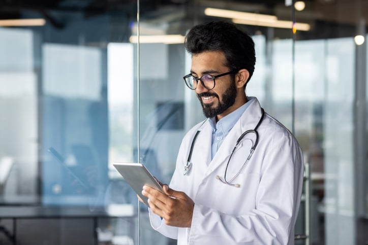 a physician smiling and looking at an ipad