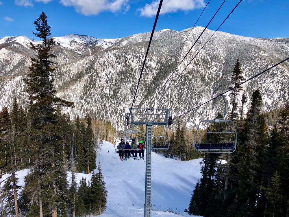 Family of four sitting on a sky lift overlooking the snowy mountains