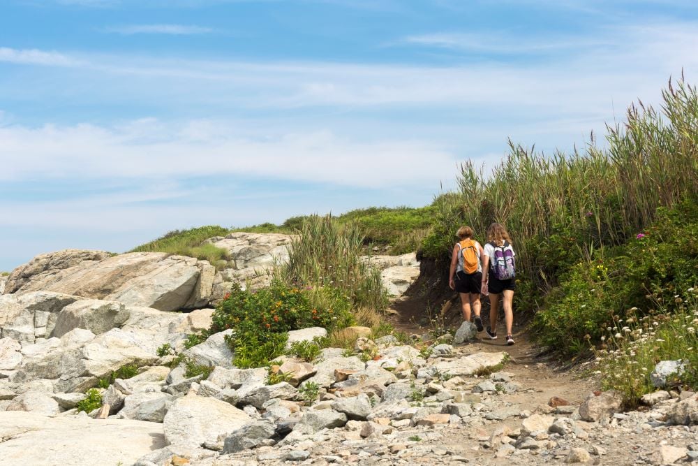 two individuals hiking near the beach