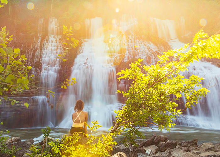 Woman sitting in front of a beautiful waterfall