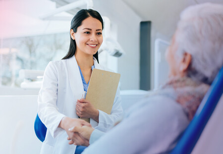 Female physician with clipboard holding patient's hand