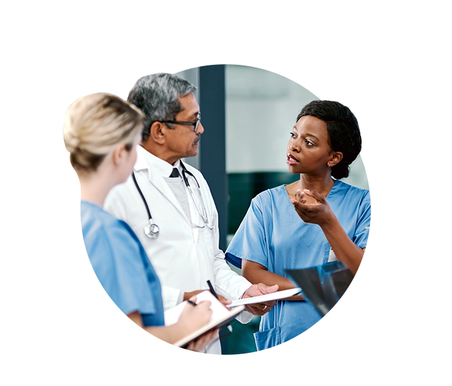 Two female nurses speaking to male physician